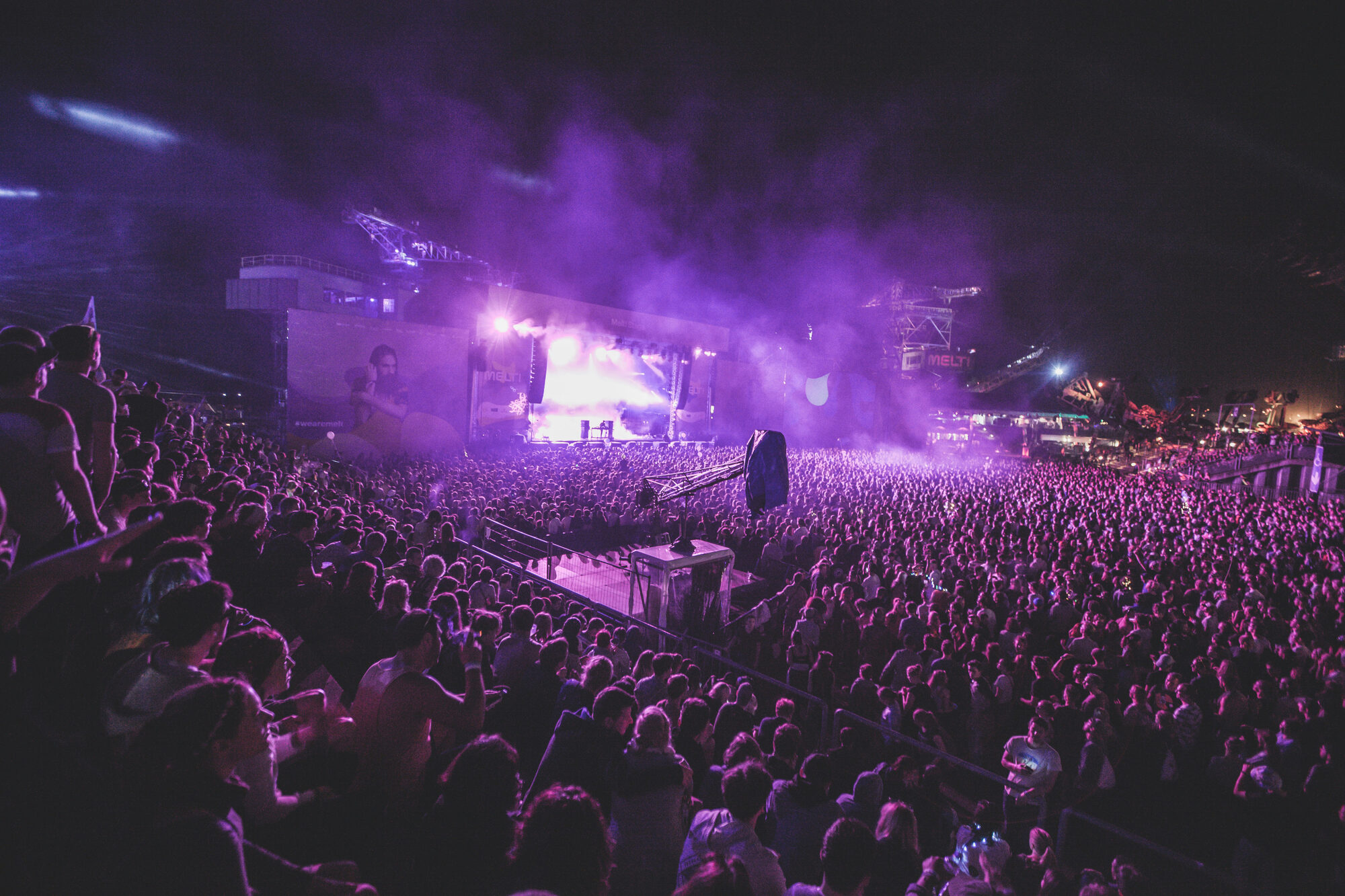 Festival crowd at sunset with hands in the air