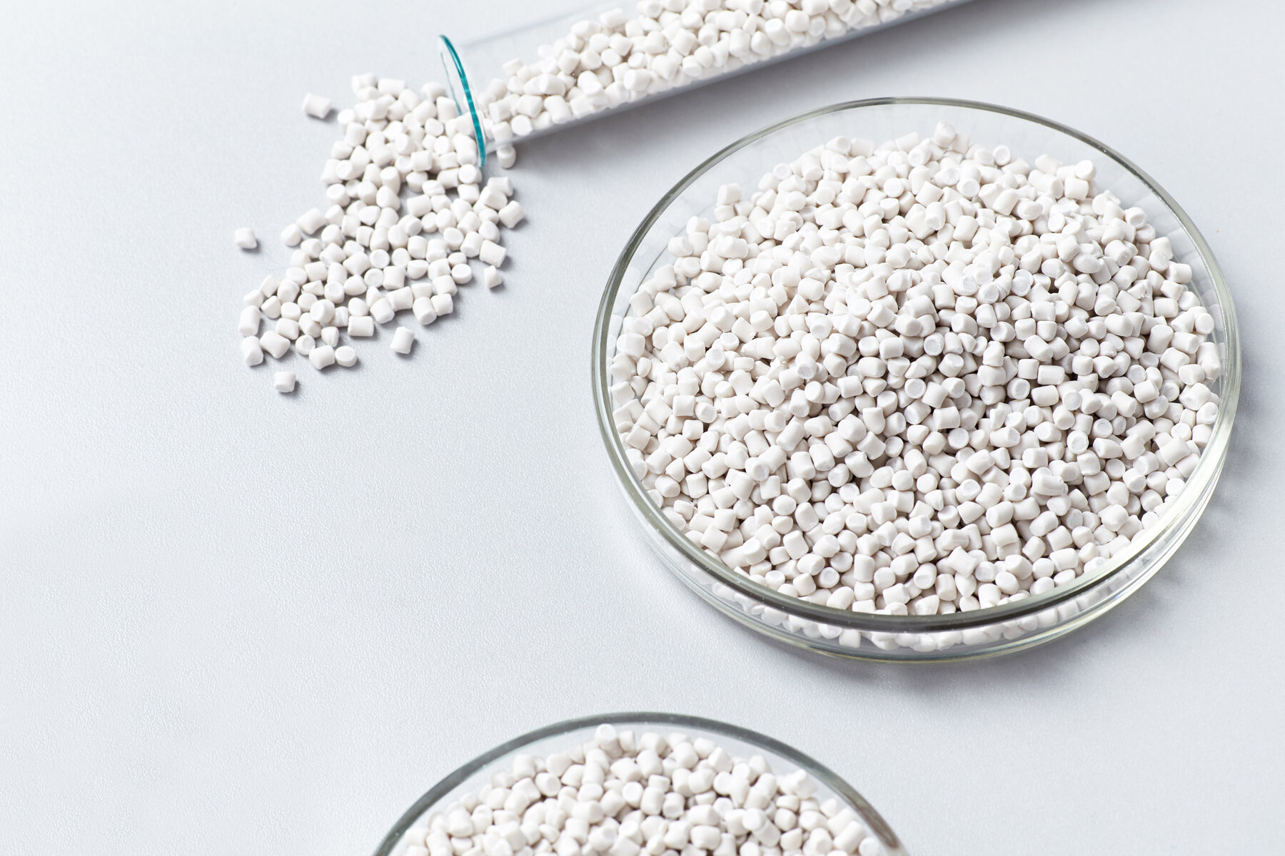 White compostable PLA pellets in petri dishes and a glass beaker